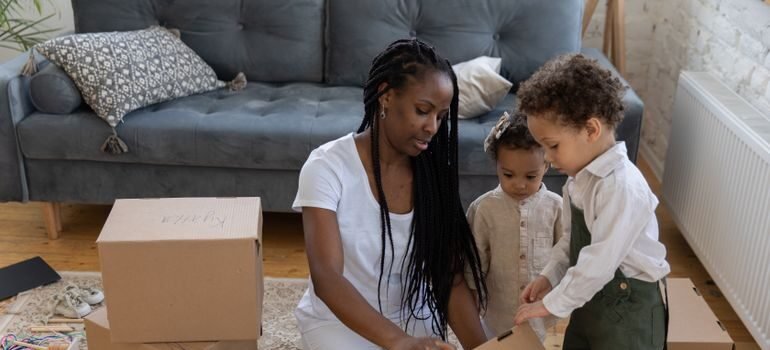 Young child placing favorite toys into a labeled moving box during family relocation preparation