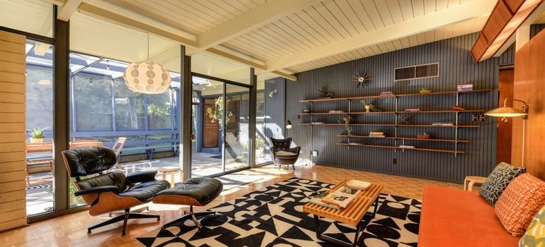 A mid-century living room with a beamed ceiling and glass walls, typical of a Palo Alto Eichler