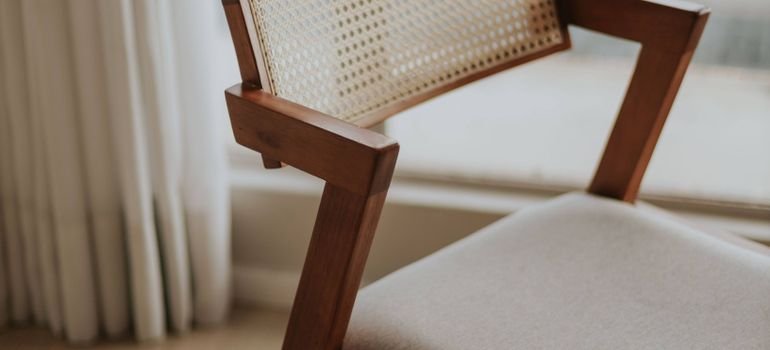 A mid-century modern wooden chair with a woven seat in soft sunlight