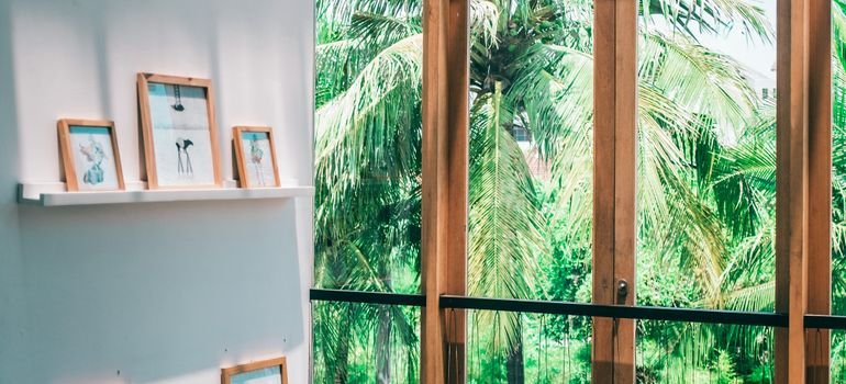 Tall glass panels in wood frames beside framed art on a white wall