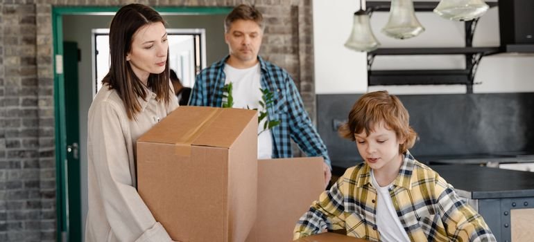 A family carrying cardboard boxes into their new home