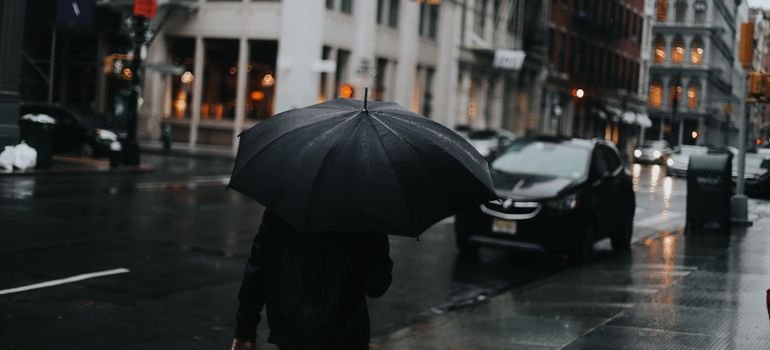 A person with an umbrella walking down a wet city street on a rainy day
