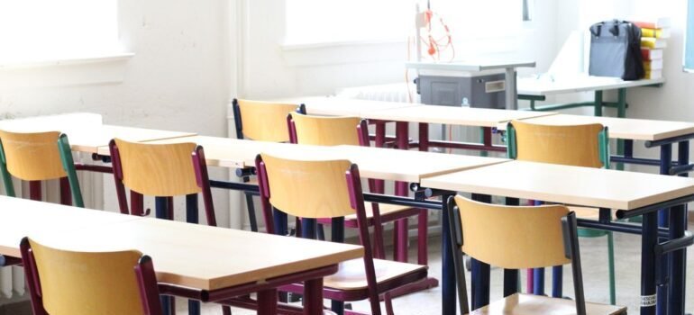 A bright empty classroom with wooden tables and chairs, ready for students.