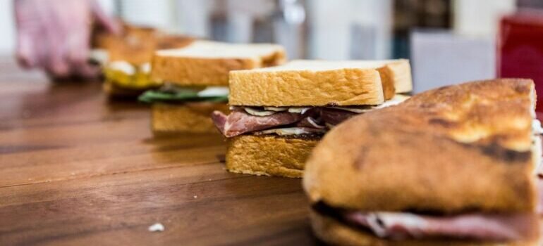 Fresh sandwiches being prepared on a wooden table, showcasing vibrant ingredients.