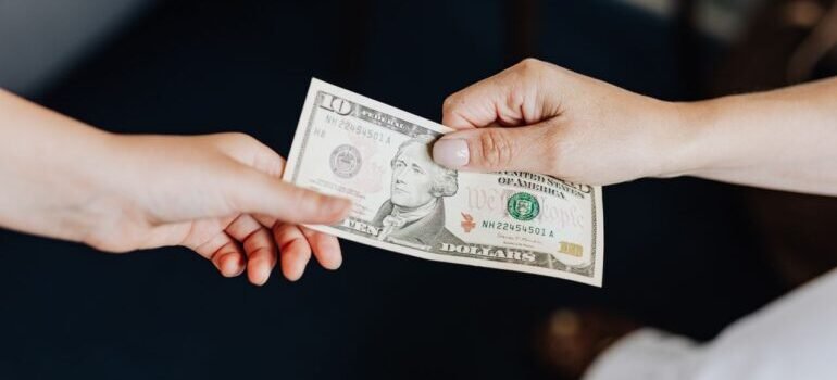 Two people exchanging a ten dollar bill in a close-up hand-to-hand transaction.
