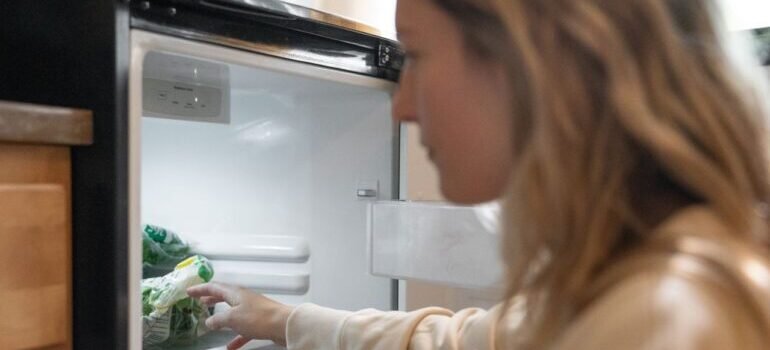 woman taking vegetables out before trying to move a refrigerator